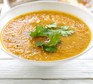 Carrot and coriander soup in a bowl garnished with fresh coriander