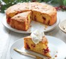 A slice of cranberry and clementine polenta cake with a dollop of zesty cinnamon cream on top