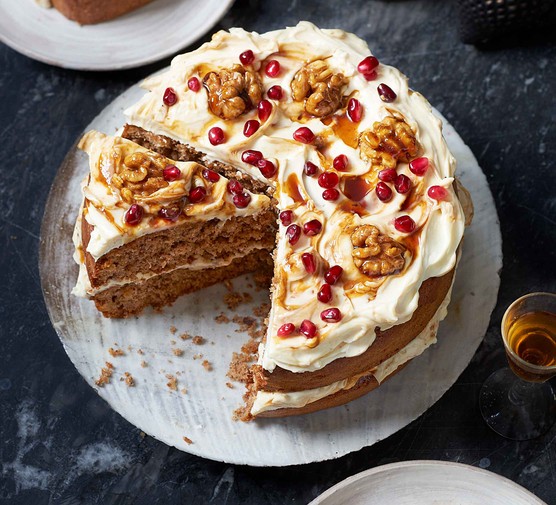 Spiced cake covered in icing, pomegranates and walnuts